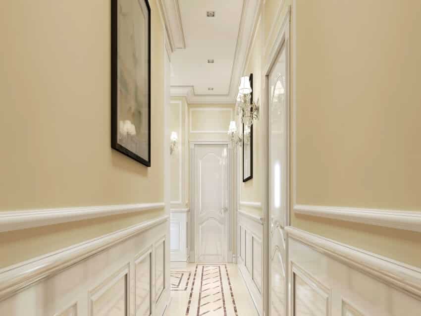 Classic style hallway with wood paneling painted in white and sconce lights
