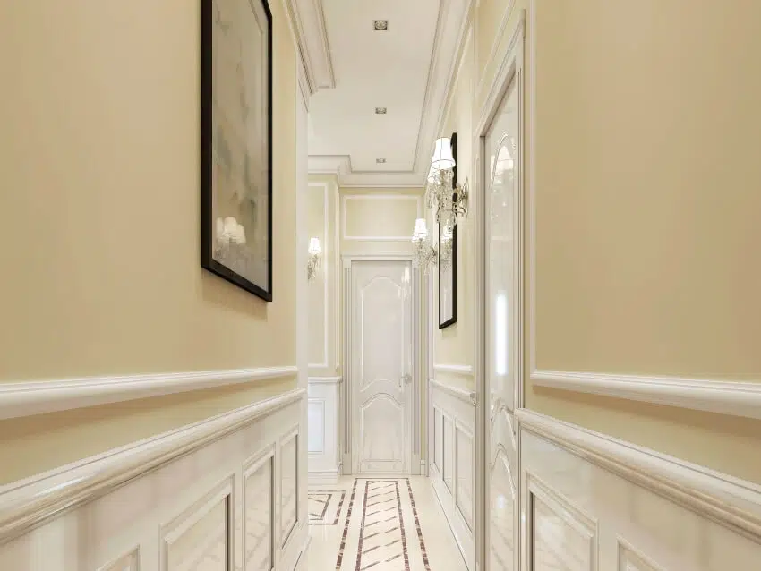 Classic style hallway with wood paneling painted in white and sconce lights 