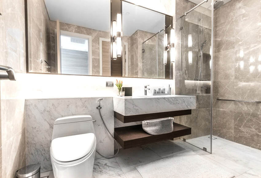 Clean bathroom with a floating vanity, wall mounted lights, and marble wall