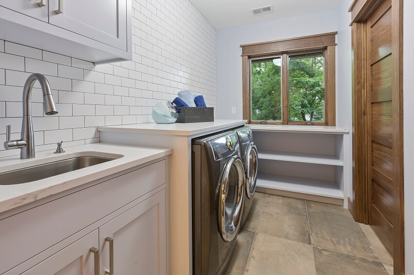 A clean laundry room with washer dryer and stainless utility sink
