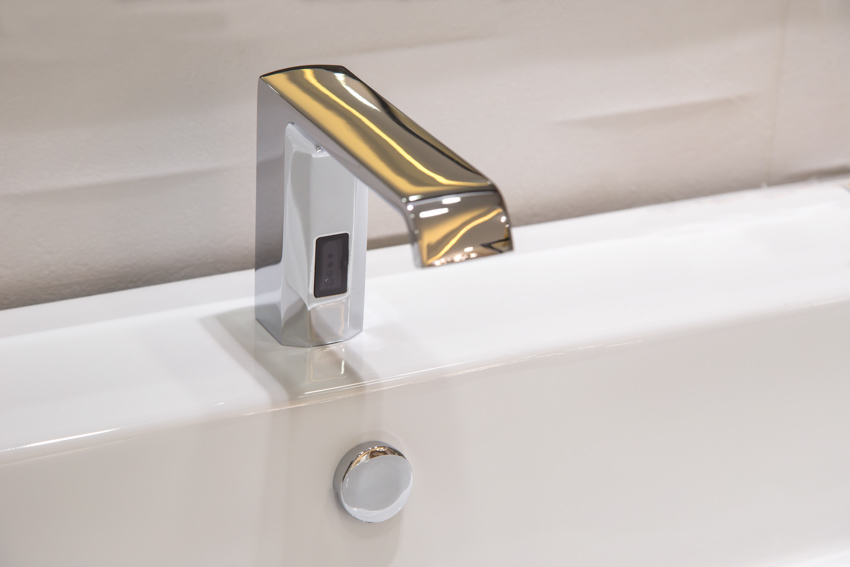 Close up image of shiny touchless bathroom faucet