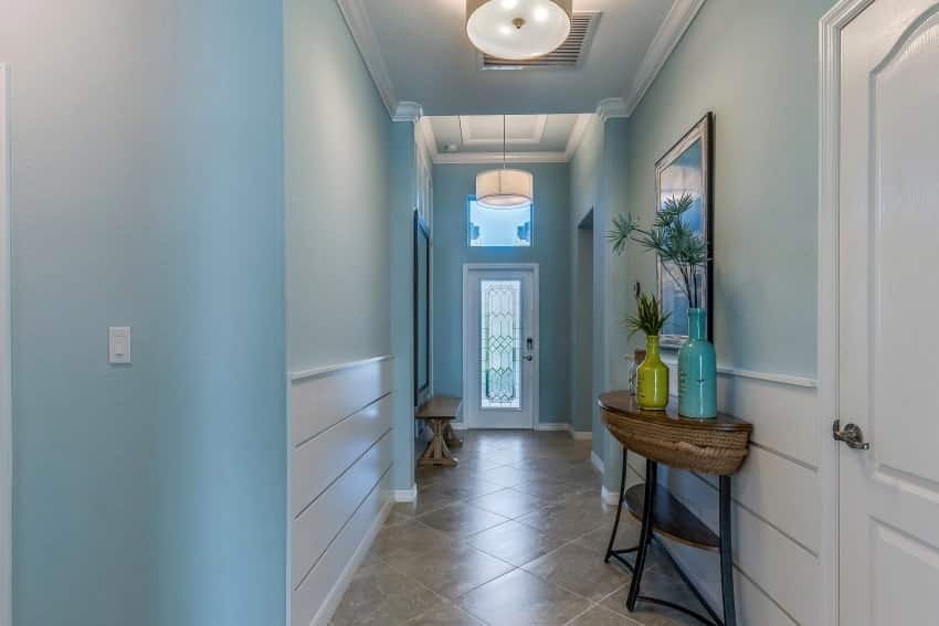 Console table, tile flooring, shiplap walls, and pendant lights in a hallway