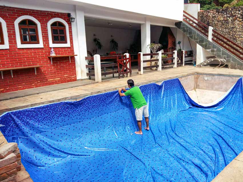 Contractor installing liner on empty swimming pool