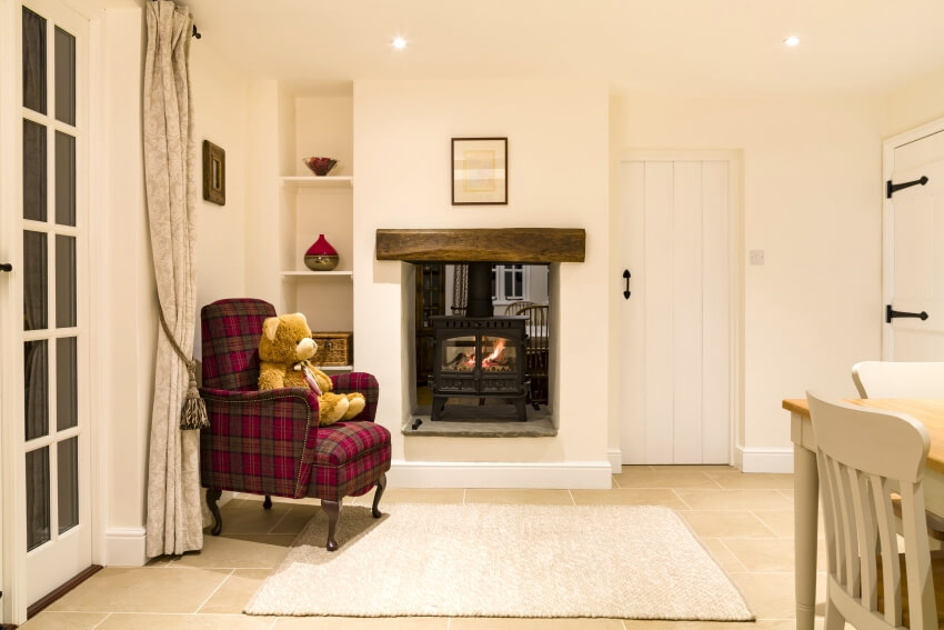 Country house interior with beige walls, red plaid armchair, and log fire