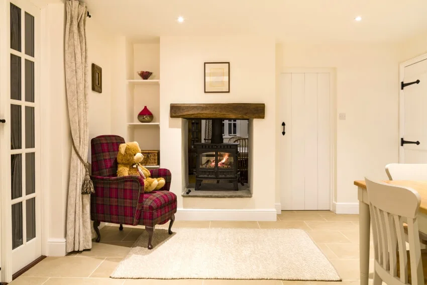 Country house with beige walls, red plaid armchair, and log fire