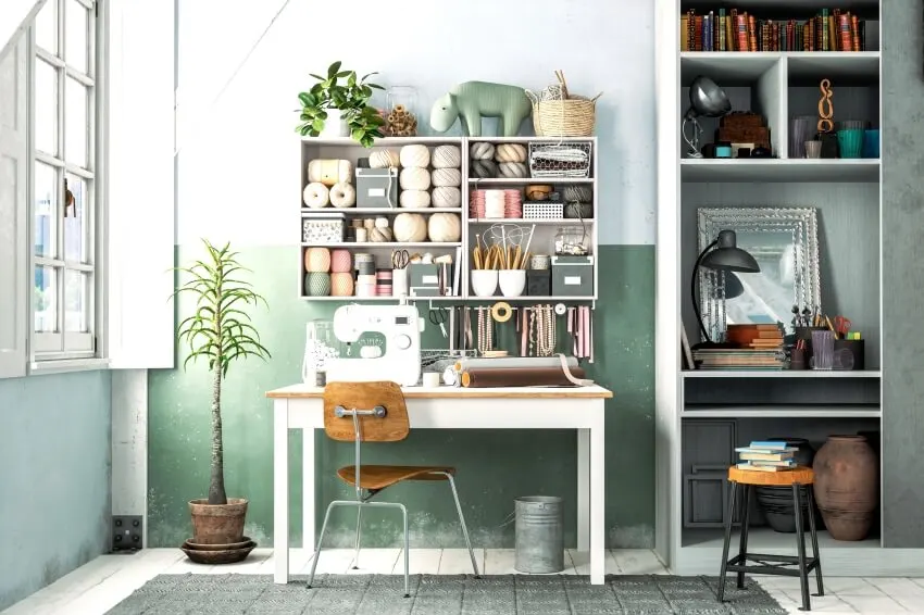 A craft room with fresh green wall paint, a built-in storage, table and chair near the window 