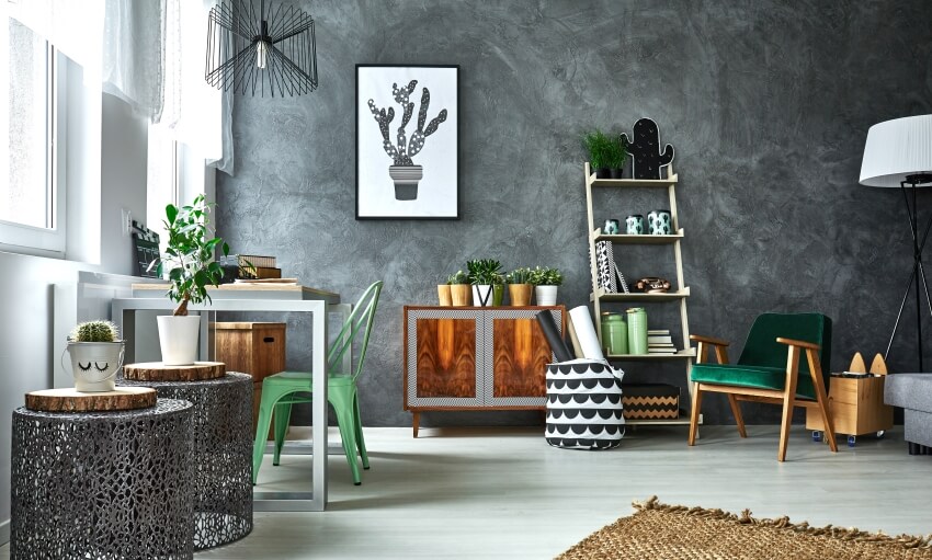 Rustic vibe craft room with grey wall stucco, metal accessories, green armchair, shelves, and a table