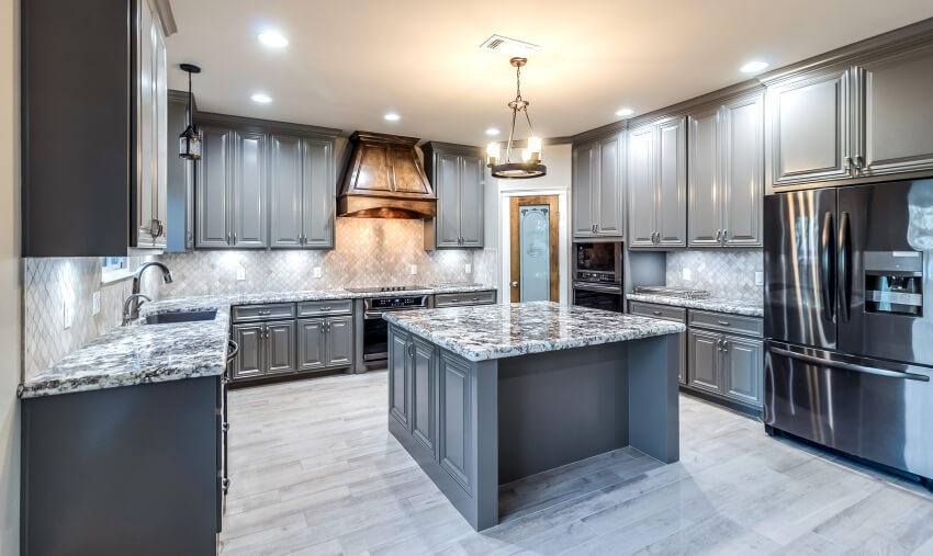 Dark grey cabinetry, tile backsplash, and granite countertops in large kitchen