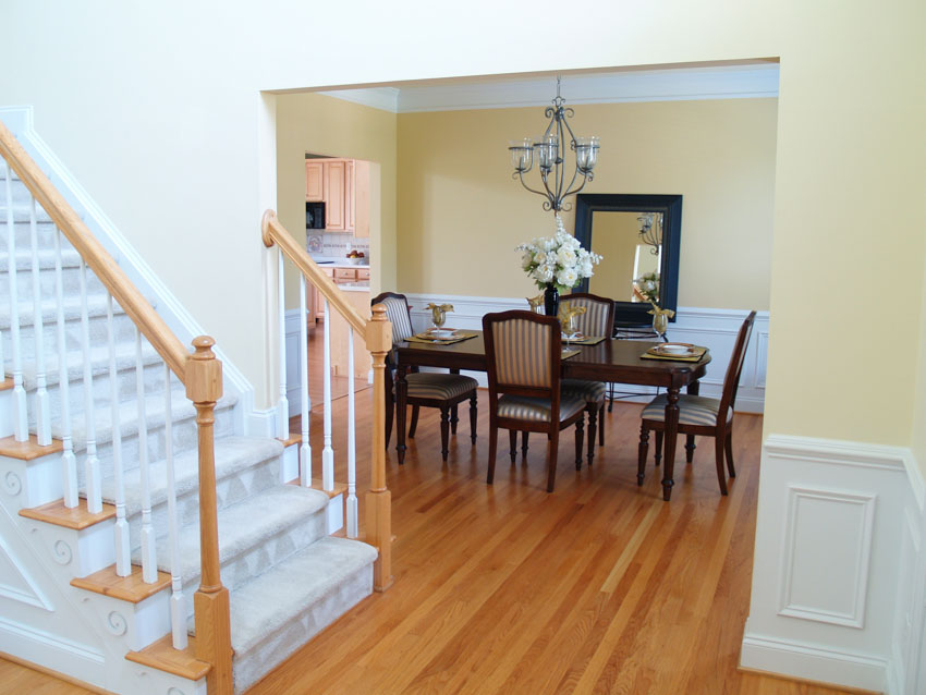Dining room near staircase with wood floor, chairs, table, and wainscoting