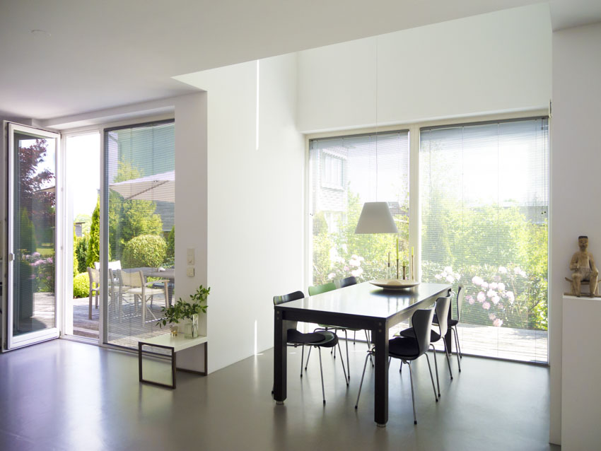 Dining room with concrete floor, windows, table, chairs, and glass door