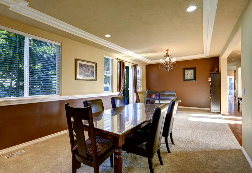 Tan wainscoting with accent wall, moldings on the ceiling and light bronw carpeting