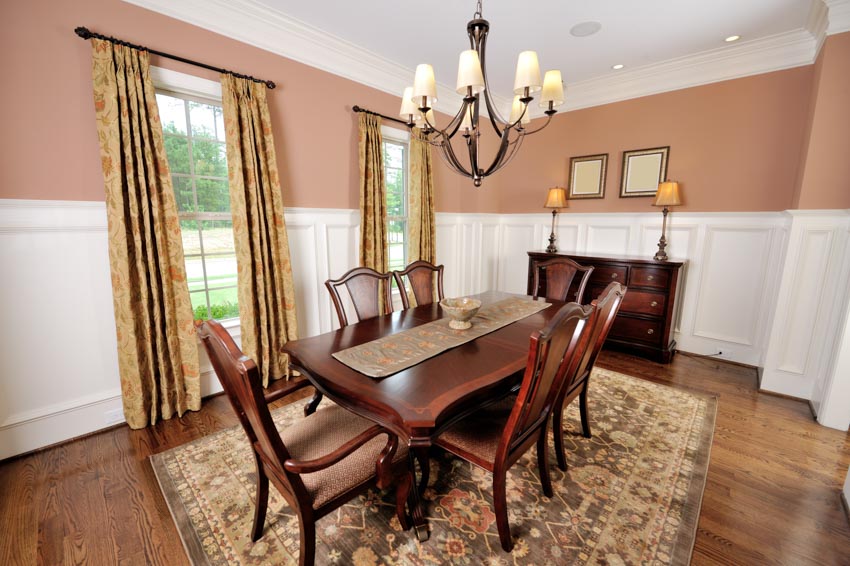 Dining room with light pink walls, table, chairs, windows, and floor rug
