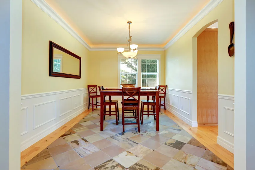 Room with tile flooring, yellow walls, wainscoting, and window