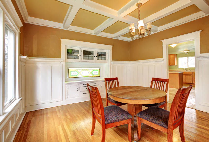 Dining room with wainscoting, coffered ceiling, round table, chairs, and wood flooring