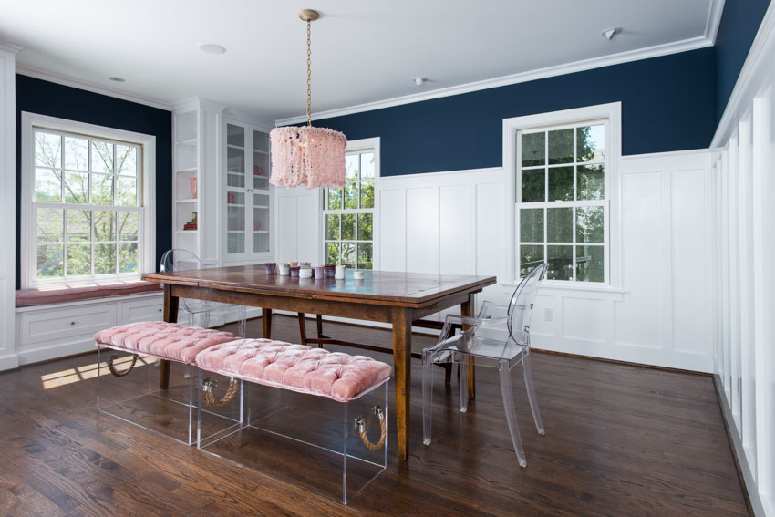 Dining room with wainscoting, wood floor, table, chairs, bench, hanging light, and windows