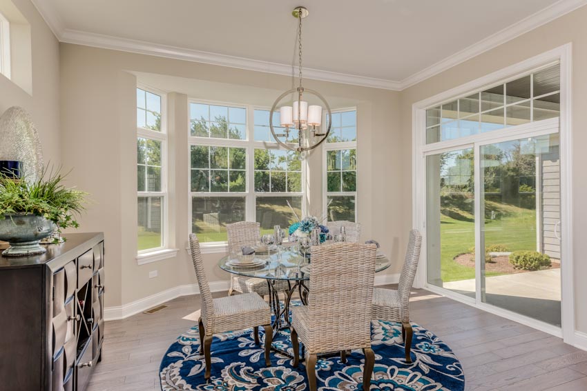 Dining room with white walls, table, chairs, pendant lights, glass door, and bay window