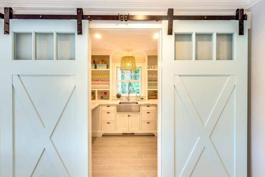 Double barn doors entry into laundry room, craft room, and pantry with stainless steel sink