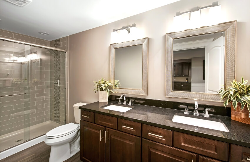 Double sink vanity with dark cabinets in a bathroom with with subway tile wall in shower
