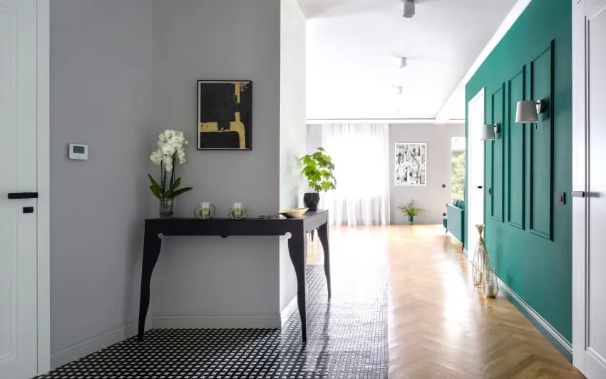 Elegant apartment corridor with green walls with molding and stylish black console table