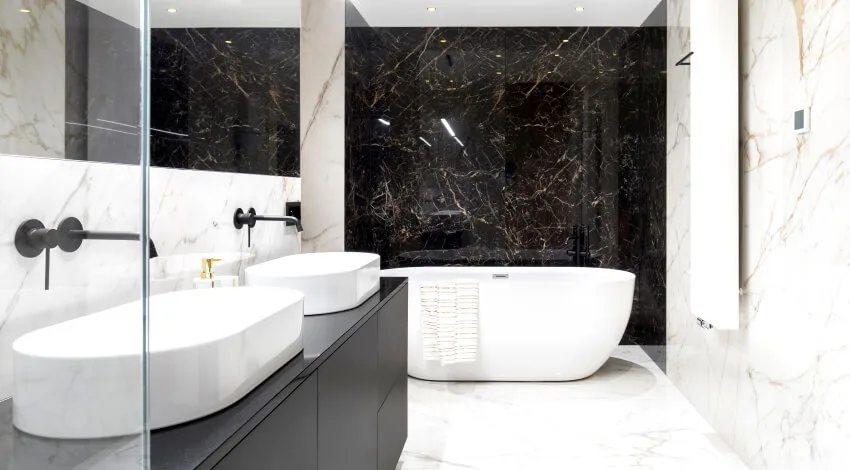 Elegant bathroom in black and white marble tiles on walls and floor, bathtub, and two wash basins