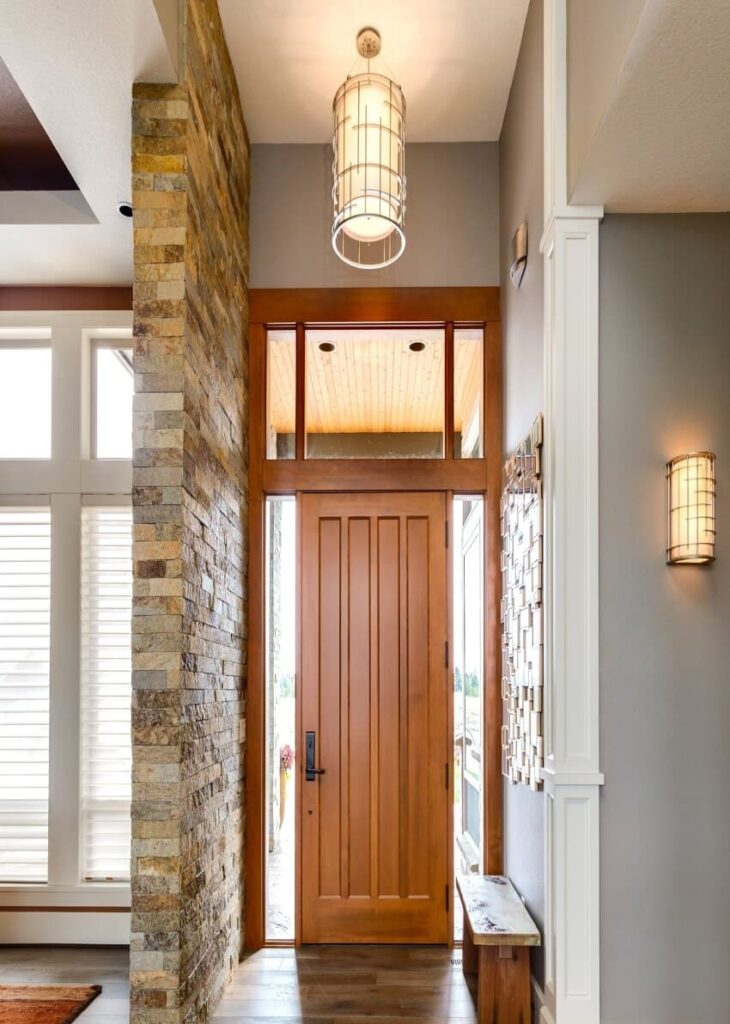 Elegant entrance hallway with stone wall, wood bench, and matching lighting fixtures