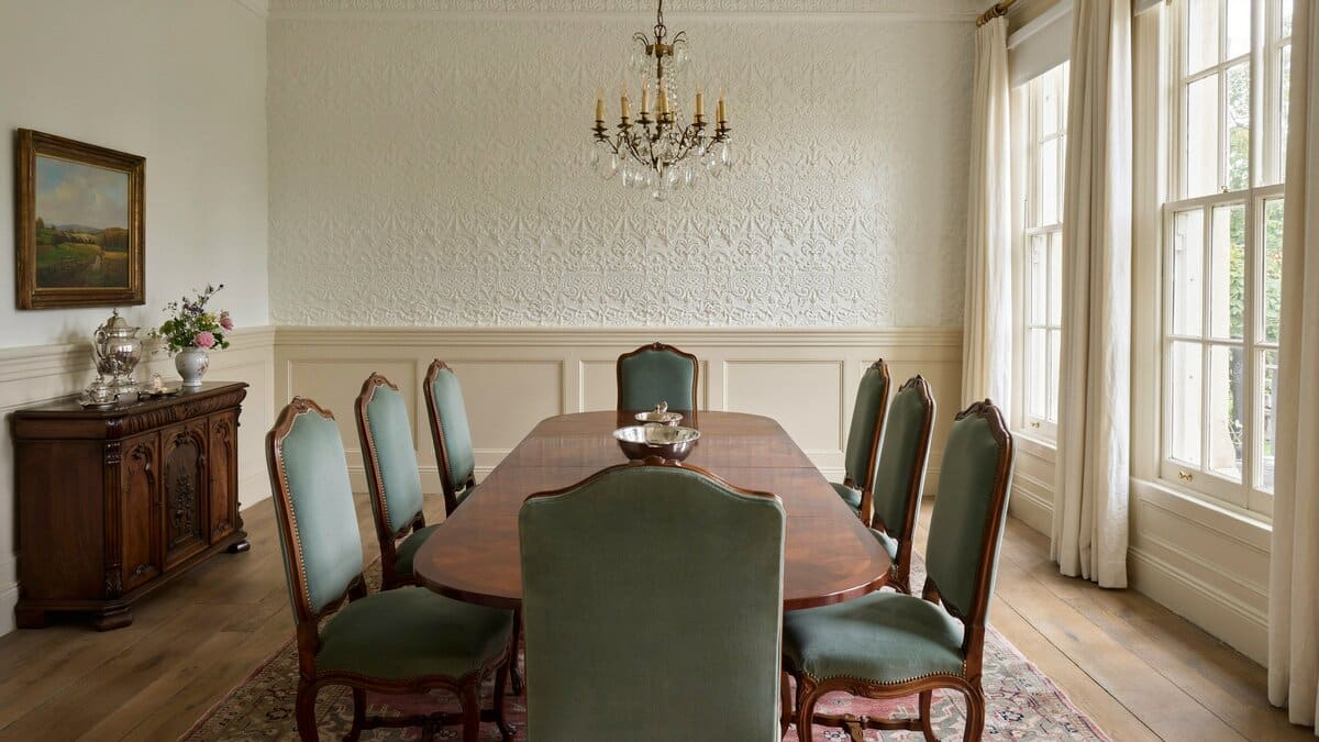 Formal dining room with white embossed textured wallpaper and green upholstered chairs