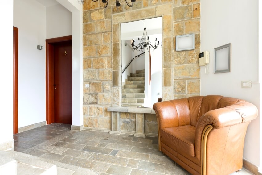Entrance hall with mirror, brown leather armchair, and limestone floor and wall