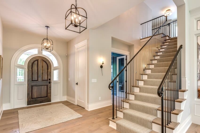Entrance hallway with gorgeous lighting fixtures, and beautiful stairs with metal railing