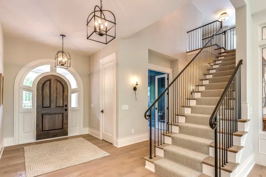 Entrance hallway with lighting fixtures and stairs with metal railing