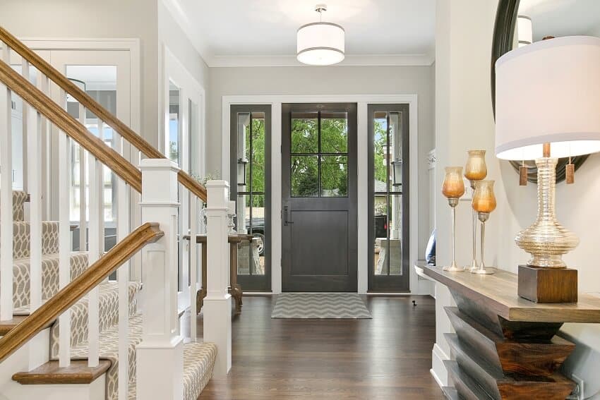 Entrance hallway with hardwood floor, table lamp on console, and staircase with wood hand rail