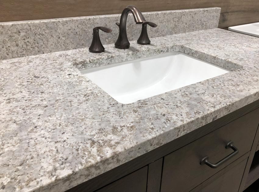 Granite bathroom countertop with sink, faucet, and wood drawers