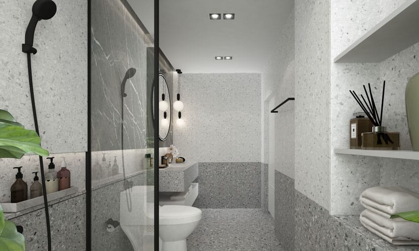 Gray bathroom with terrazzo shower wall, showerhead, toilet, and mirror