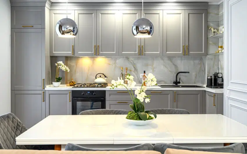 Grey and white classic kitchen interior with dining table, pendant lights, and marble backsplash