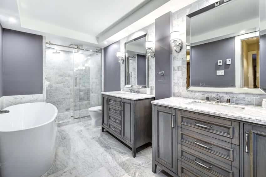 Grey bathroom with freestanding tub, wall lights, and marble countertops, wall and floor