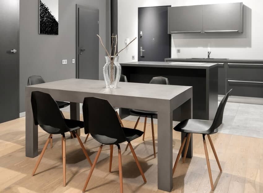 Grey dining table with modern black chairs and stylish glass vase in minimalistic grey kitchen