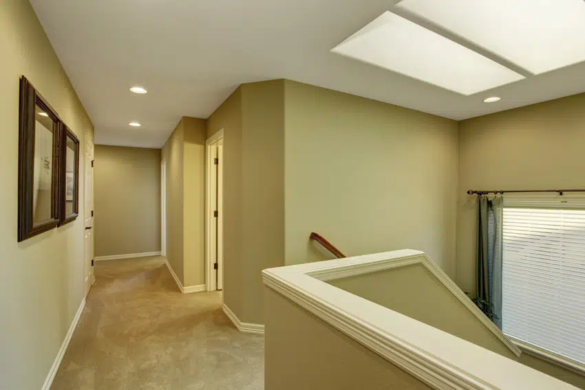 Hallway with carpet floors, beige walls, and skylight windows