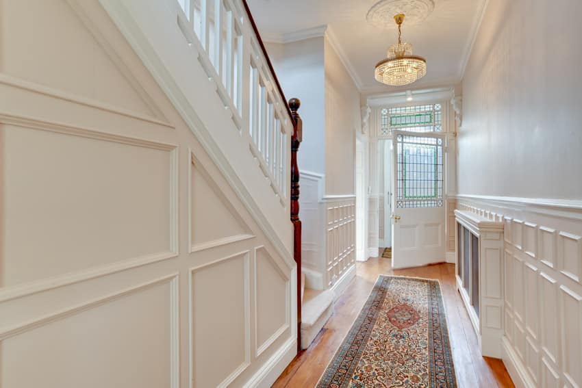 Hallway with front door, wood flooring, wainscoting, chandelier, and staircase