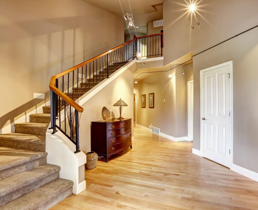 Hallway with staircase, wood railing, wooden floors, and white door