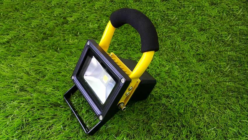Heavy-duty work flood light with handle, and bracket on grassy field