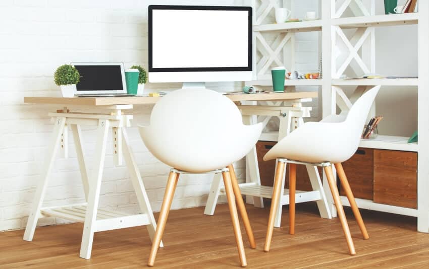 Home office with wooden chairs and table, shelves, and white brick wall