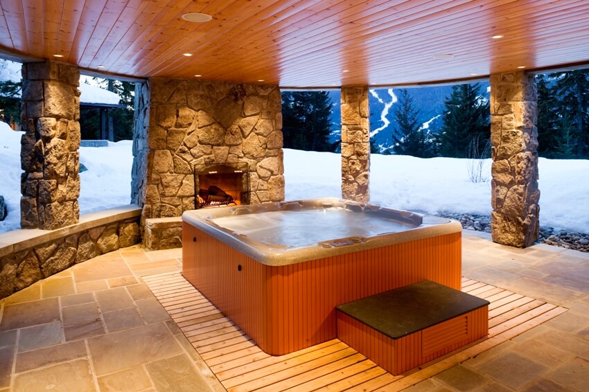 Hot tub enclosed with stone posts and a fireplace