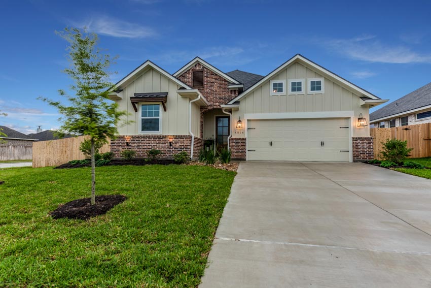 House with garage, windows, vertical siding, and epoxy coated driveway