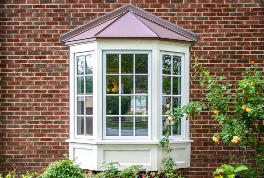 Bay window, hedge plants, and brick wall