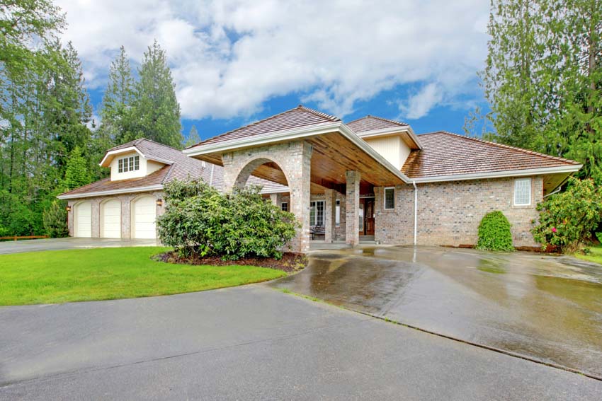 House exterior with epoxy driveway, front porch, dormer, low pitched roof, and lawn