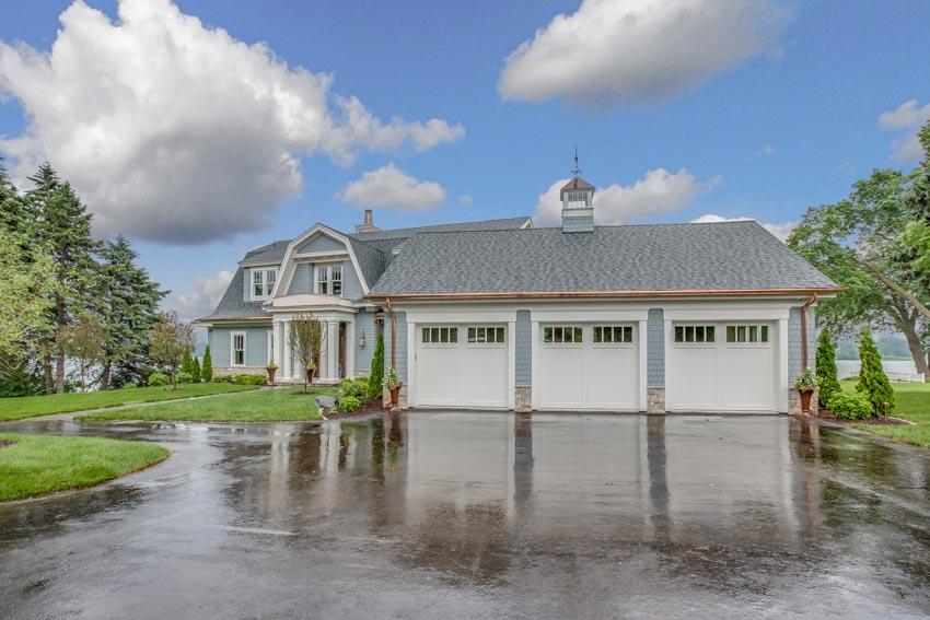 House exterior with multiple garage doors, cupola, and epoxy driveway