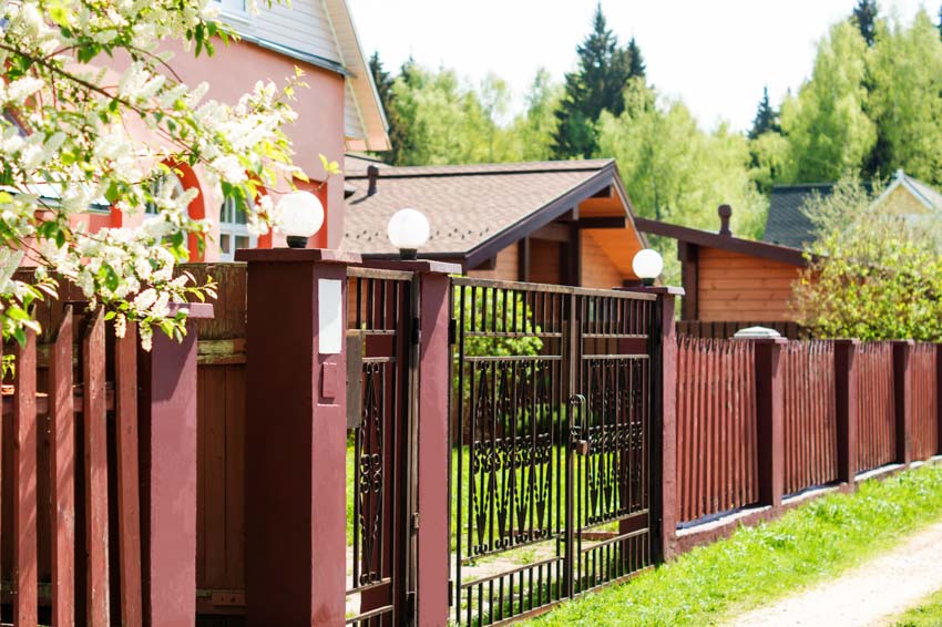 Steel gate and mahogany painted fence with a view of the house