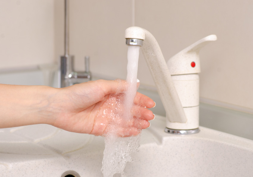 Individual washing hand under plastic faucet