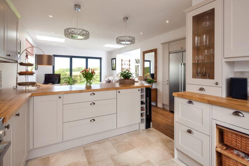 Kitchen area with white shaker cabinets, tile floor, wood slab countertops, and view of the living room