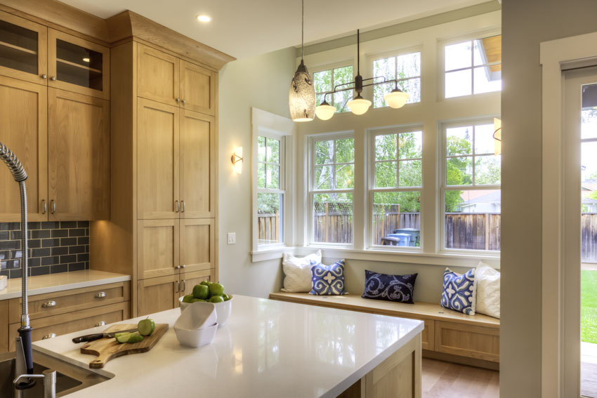 Kitchen with bay window, nook, countertop, cabinets, pendant lights, and backsplash