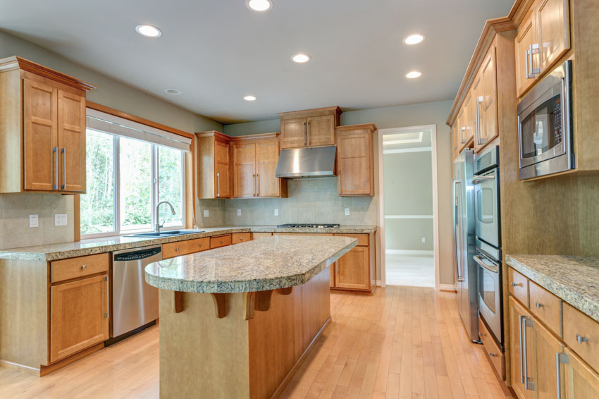Kitchen with center island, countertop, wood floor, honey oak cabinets, windows, and ceiling lights